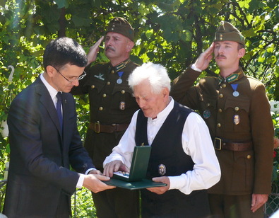 Bartha Mihály sepsiszentgyörgyi otthonában, magyar és székely zászlóval díszített udvarán átveszi a kitüntetést. Fotó: Szekeres Attila